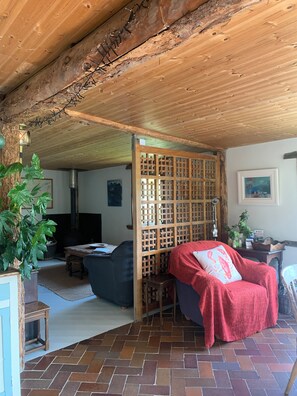 Ett mysigt vardagsrum med ett träpanelat tak, en öppen spis, en soffa, en röd filt och en trävägg som avskärmning.