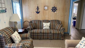 Un salon chaleureux avec un canapé à motifs écossais, un fauteuil assorti et un tapis à motifs.