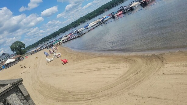Une plage de sable avec une étendue d’eau, des chaises de plage et des parasols.
