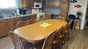 Une cuisine avec des meubles de rangement en bois, un four à micro-ondes, un évier et une table à manger avec des chaises.