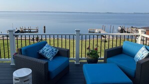 Una terraza con mobiliario de mimbre y vista a un lago tranquilo.