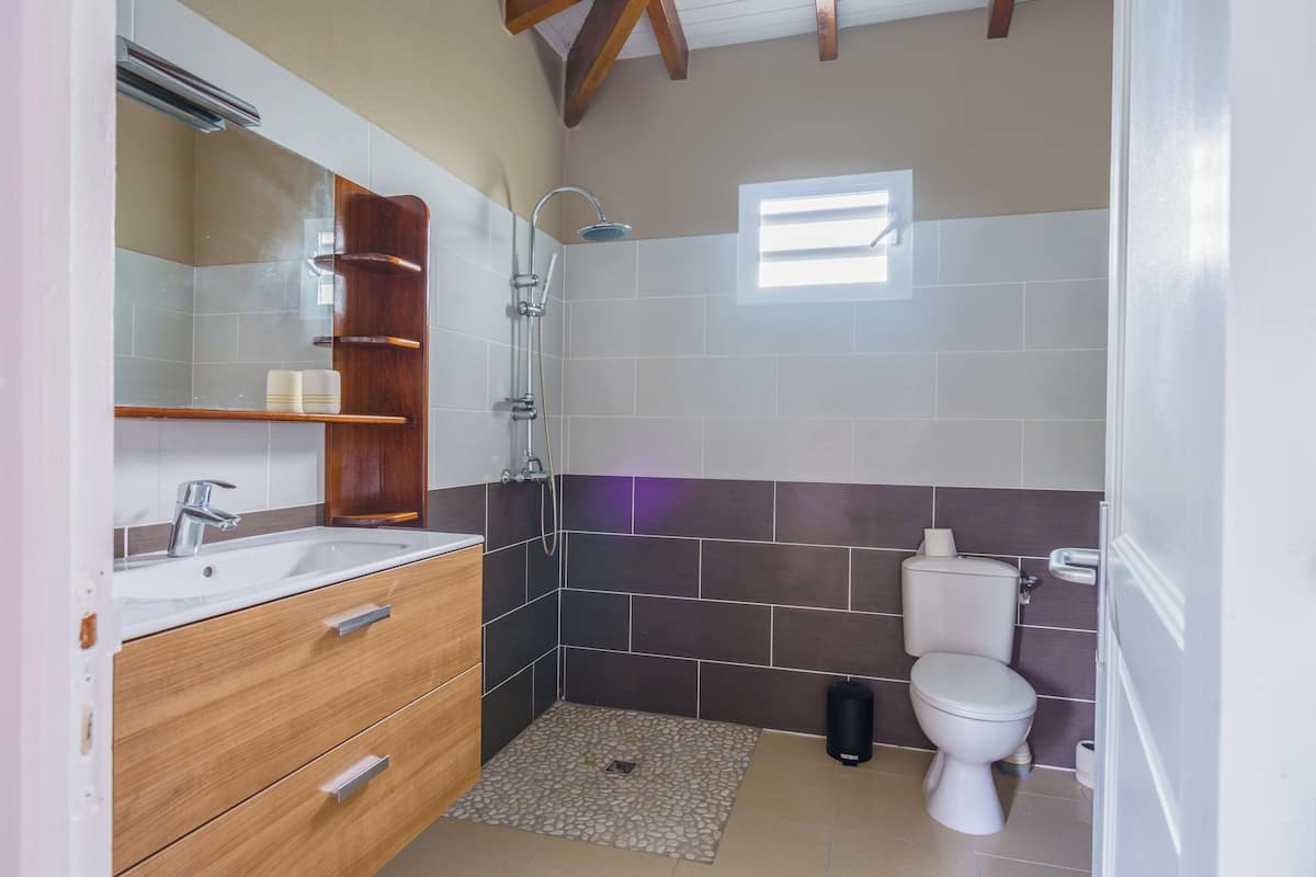 A bathroom with a shower, toilet, sink, and wooden vanity.