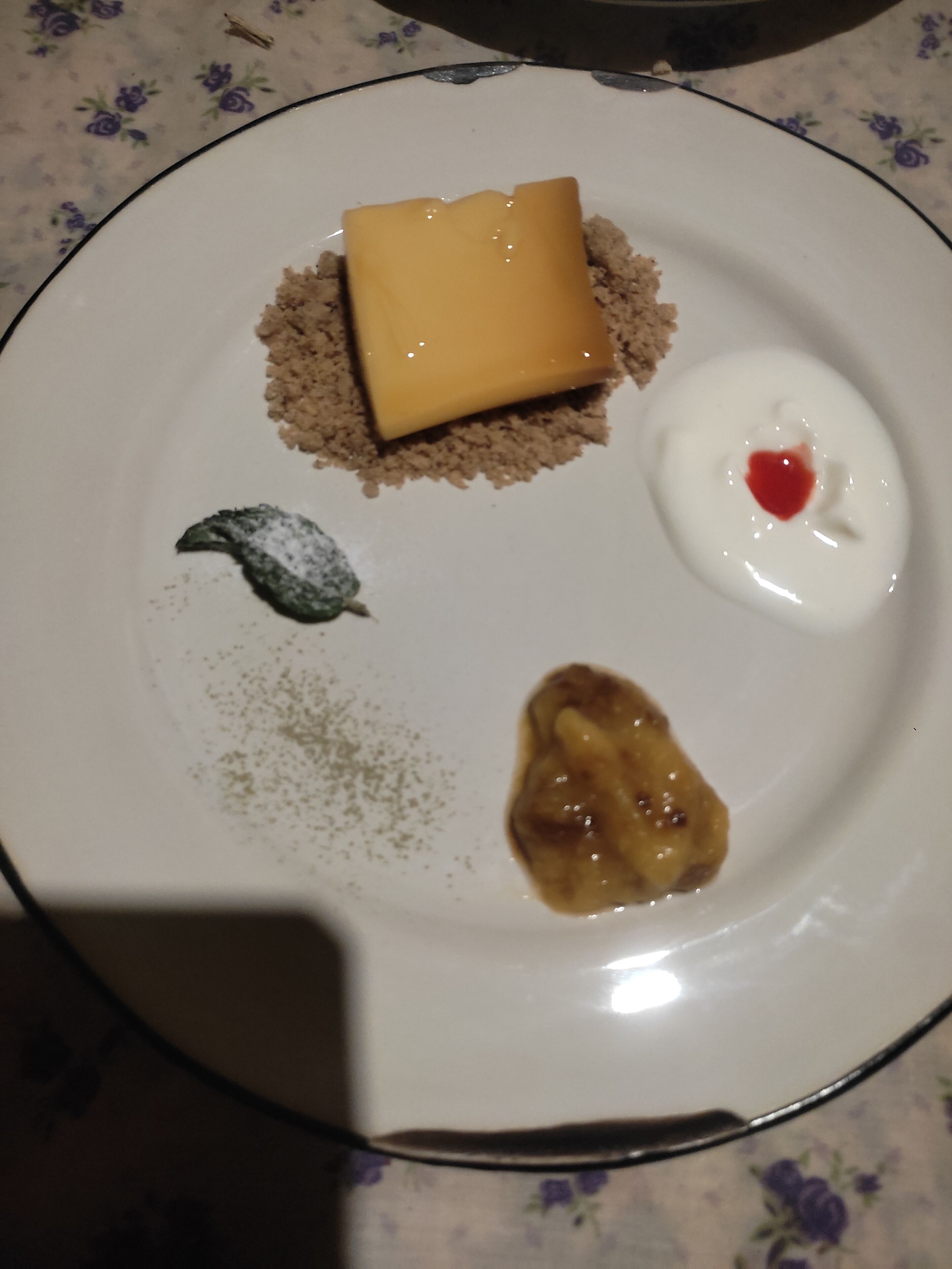 Un plato con varios postres, incluyendo un trozo de pastel, una cucharada de crema con cereza y un dulce cubierto de chocolate.