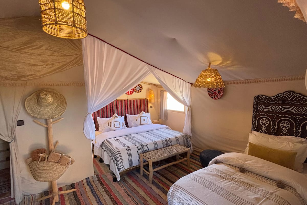 Une chambre à coucher accueillante, avec un lit à baldaquin, un petit banc et un panier en osier.