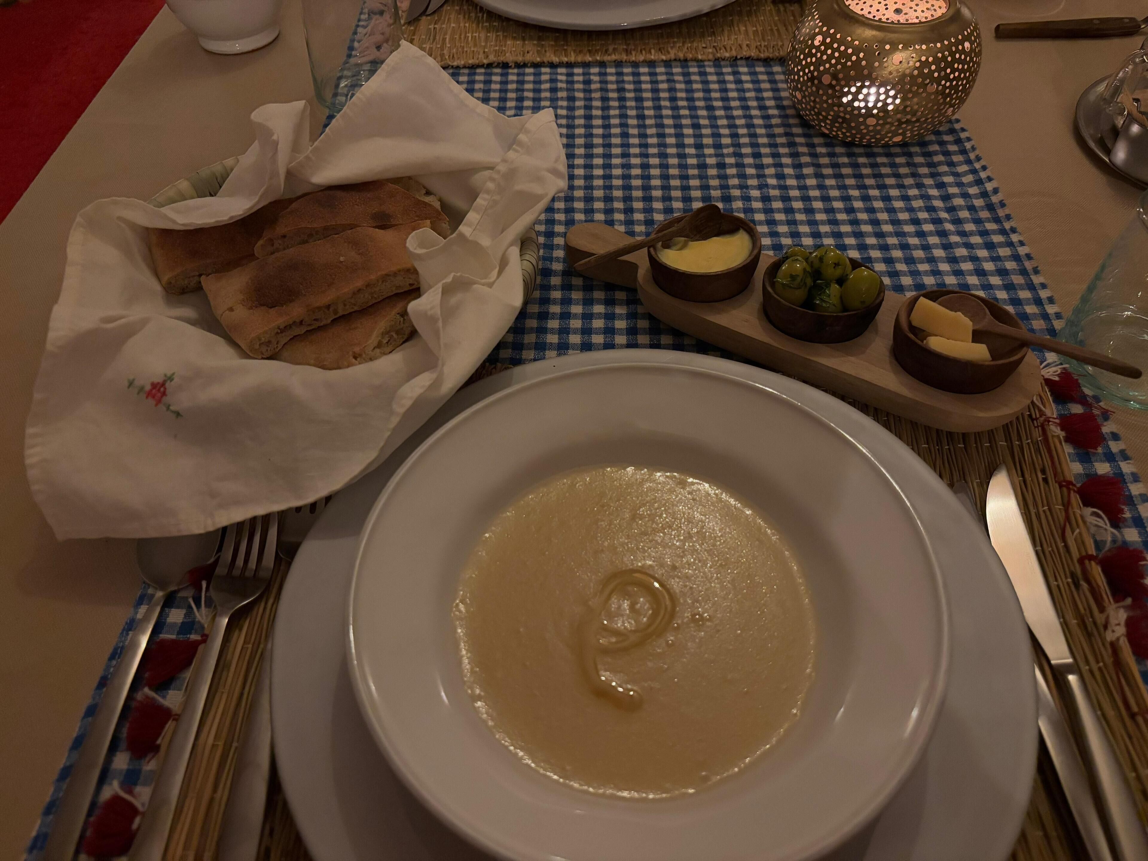 A table set with a bowl of soup, bread, and small bowls of condiments.