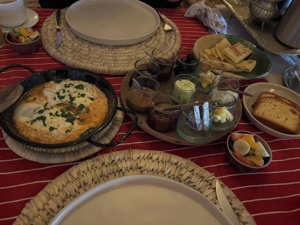 A breakfast setting with a variety of dishes including a skillet with eggs, toast, and fruit.
