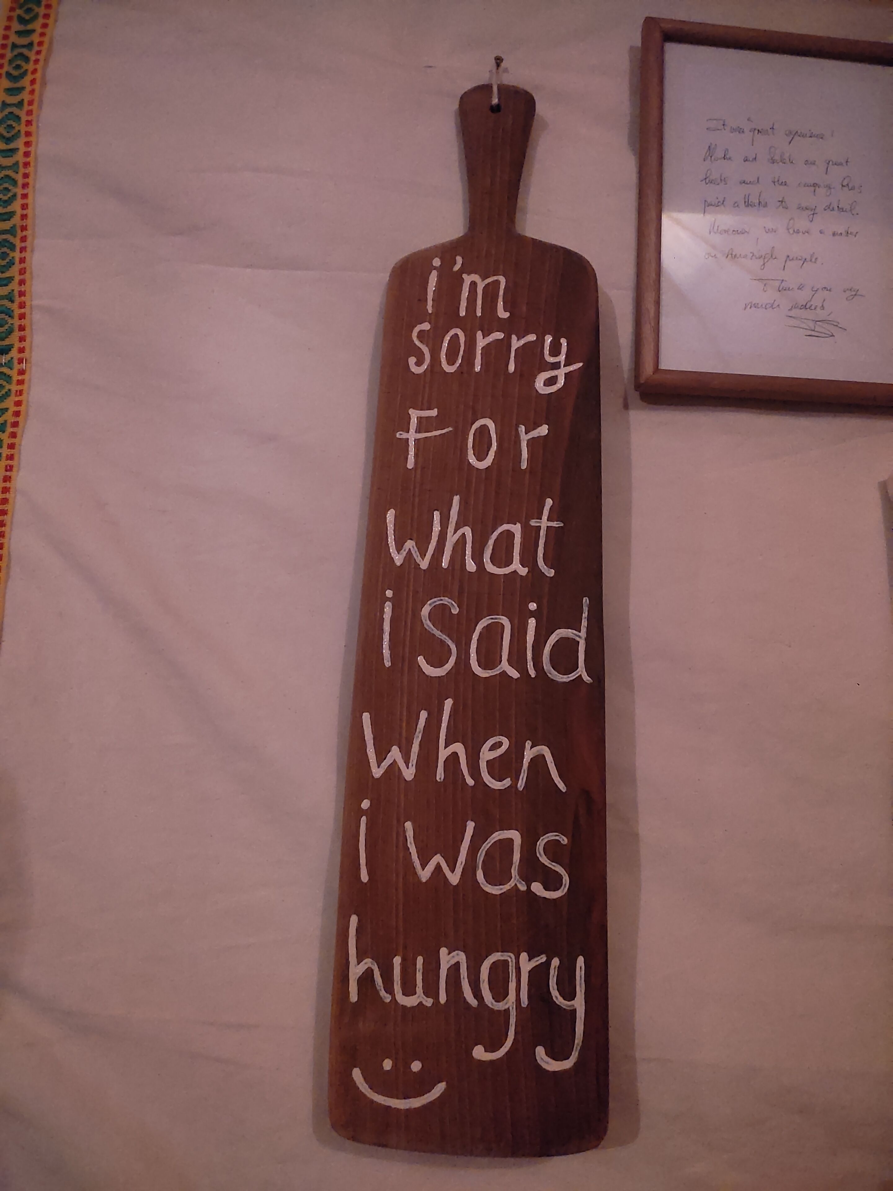 A wooden sign with a handwritten message apologizing for past comments made when hungry.