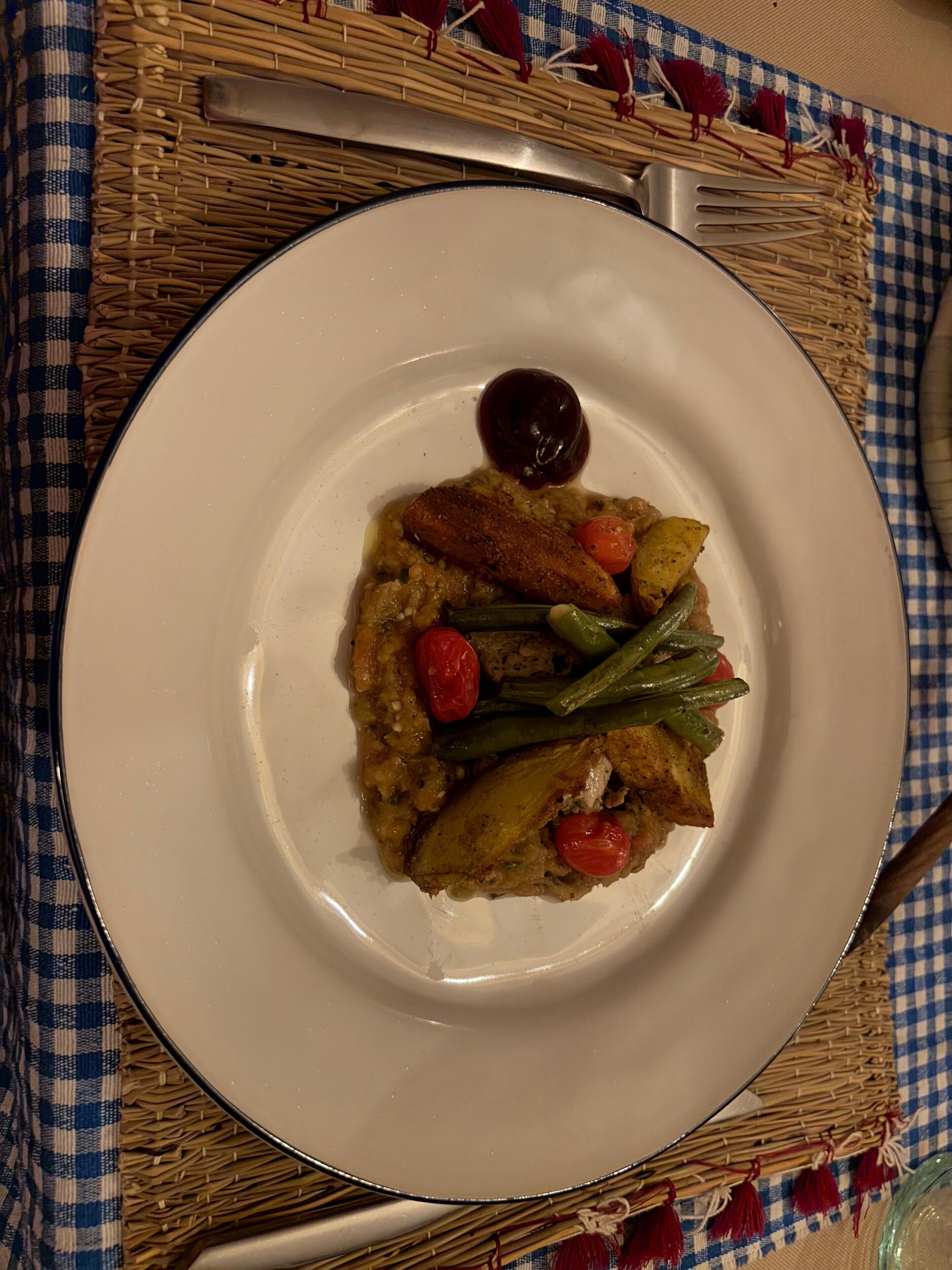 A plate of food with a variety of vegetables and a small dollop of sauce on a white plate.
