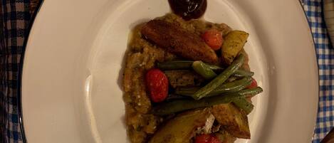 Un piatto di cibo con diversi tipi di verdure e un piccolo cucchiaio di salsa su un piatto bianco.