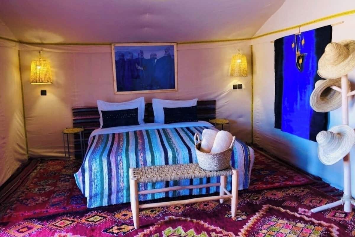 Une pièce confortable avec un lit, un banc et un porte-chapeaux fixé au mur.