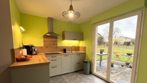 Une cuisine avec un plan de travail en bois, une cuisinière encastrée, un évier et une poubelle. Il y a une fenêtre donnant sur l’extérieur.