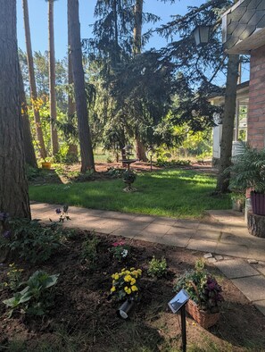 Un jardin avec un sentier, des arbres et un bâtiment à la façade en briques.