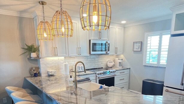 A modern kitchen with a large island, bar stools, and pendant lighting. - 2-bedroom Condo in lovely Siesta Key Beach minimum 1 Month 55 & over Second Unit (Sarasota)