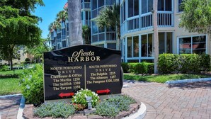 A sign for Fiesta Harbor with directions to various locations. - 2-bedroom Condo in lovely Siesta Key Beach minimum 1 Month 55 & over Second Unit (Sarasota)