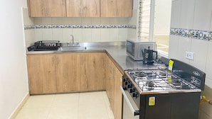 Una cocina con armarios de madera, estufa a gas, microondas y un lavamanos.