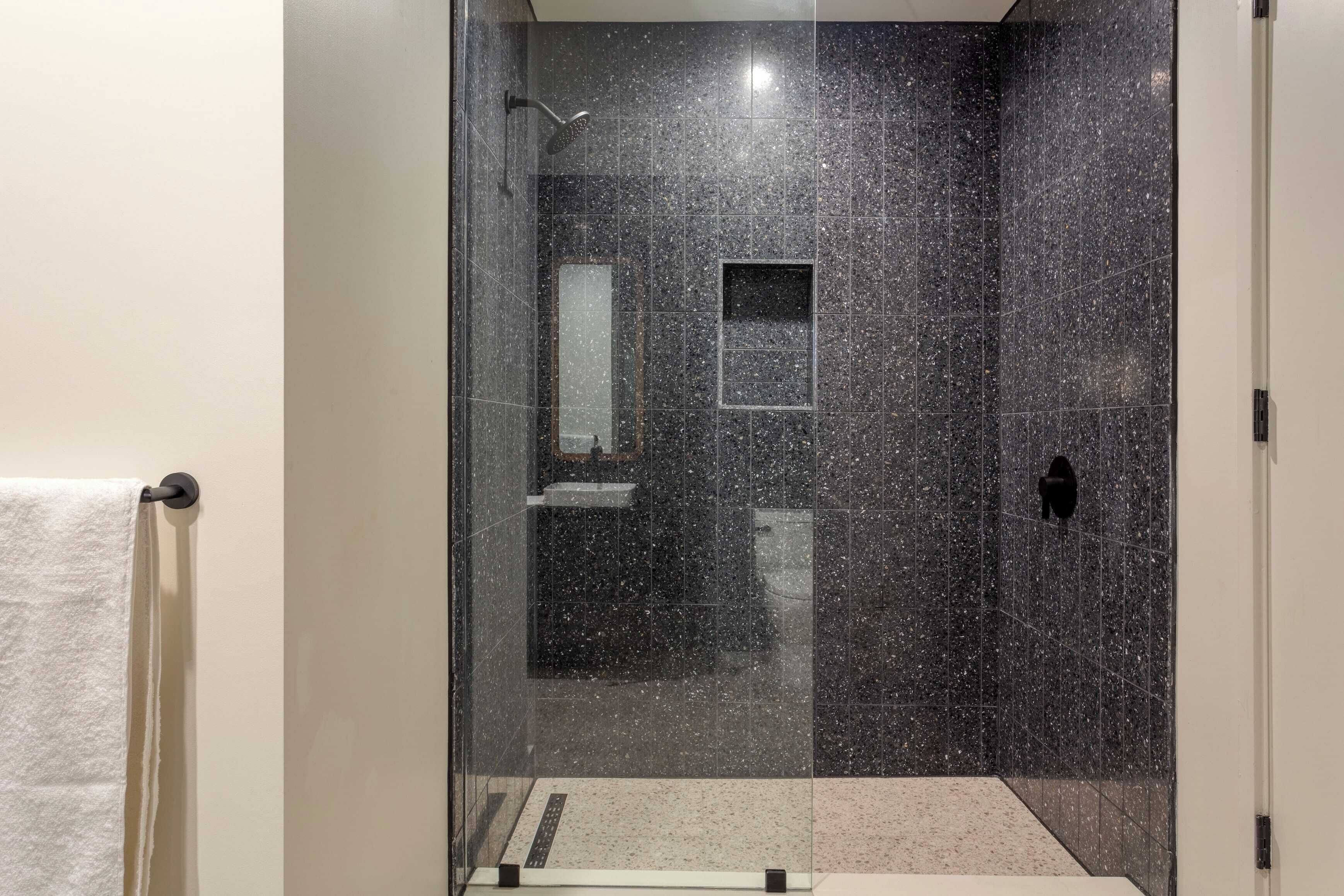 A modern bathroom with a glass-enclosed shower, a small mirror, and a towel rack.
