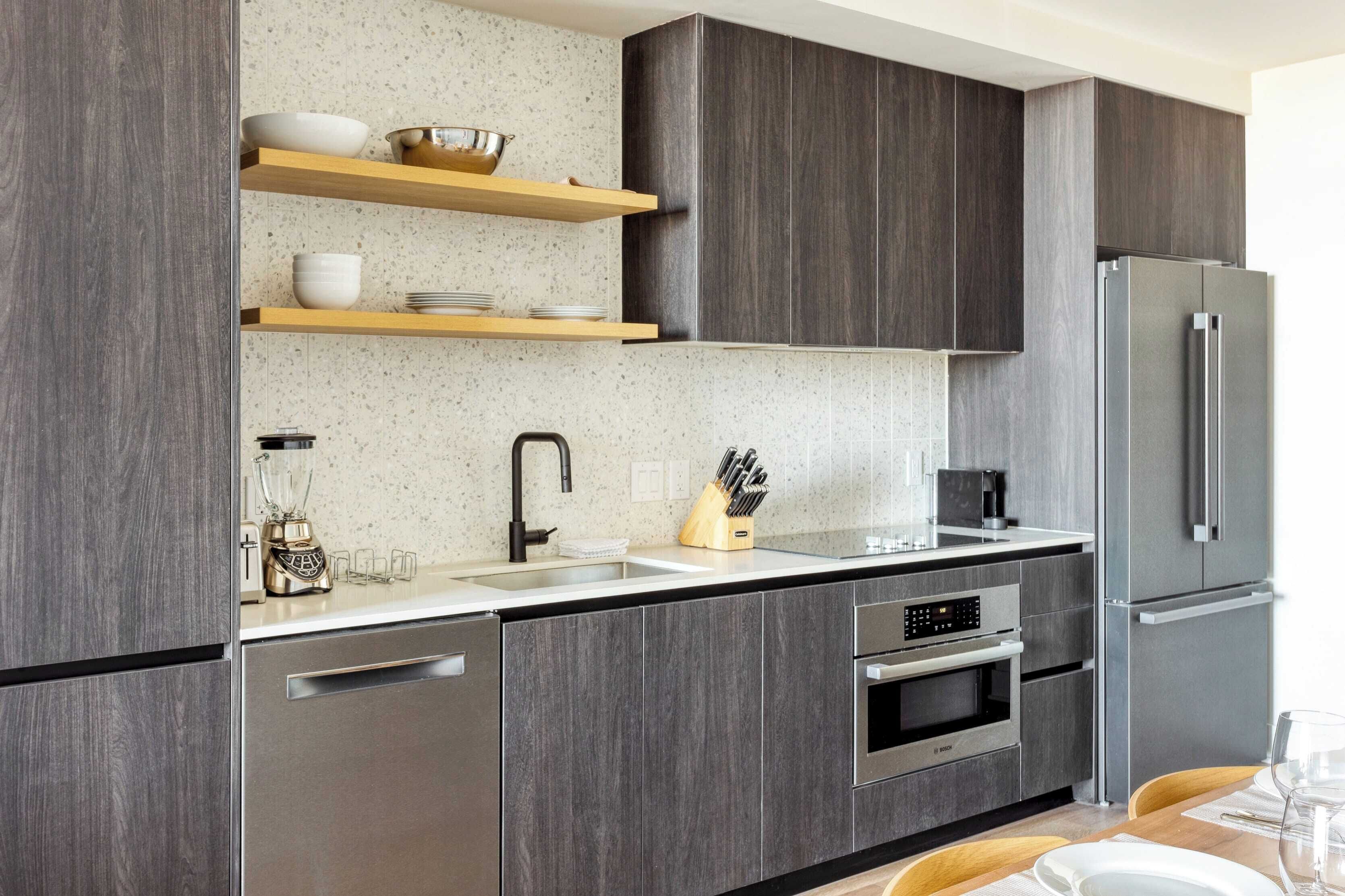A modern kitchen with dark wood cabinets, stainless steel appliances, and a granite countertop.