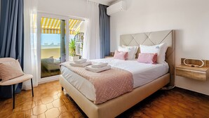 Une chambre d’hôtel avec un grand lit, une chaise, une table de chevet et une vue sur l’extérieur.