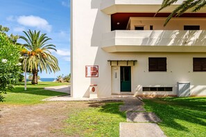 A two-story building with a green door, a small outdoor seating area, and a palm tree in the foreground. - Inema Houses Amazing Sea View (Lagos)