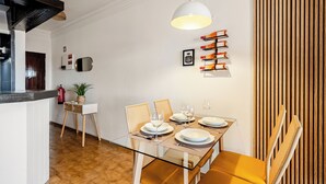 Un coin repas avec une table en verre, des chaises en bois et un luminaire suspendu.