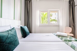 A hotel room with a bed, pillows, a chair, and a window with curtains. - Inema Houses Amazing Sea View (Lagos)