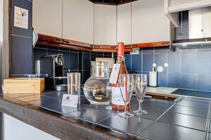 A kitchen counter with a bottle of wine, two glasses, a glass carafe, and a wooden box. - Inema Homes: Stunning Ocean Views, Inema Homes (Lagos)