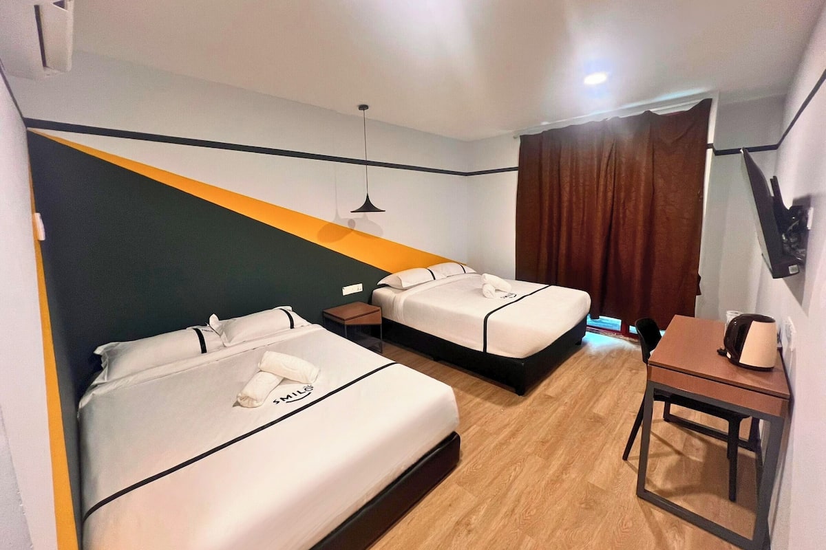 Une chambre d’hôtel avec deux lits, un bureau et une télévision.
