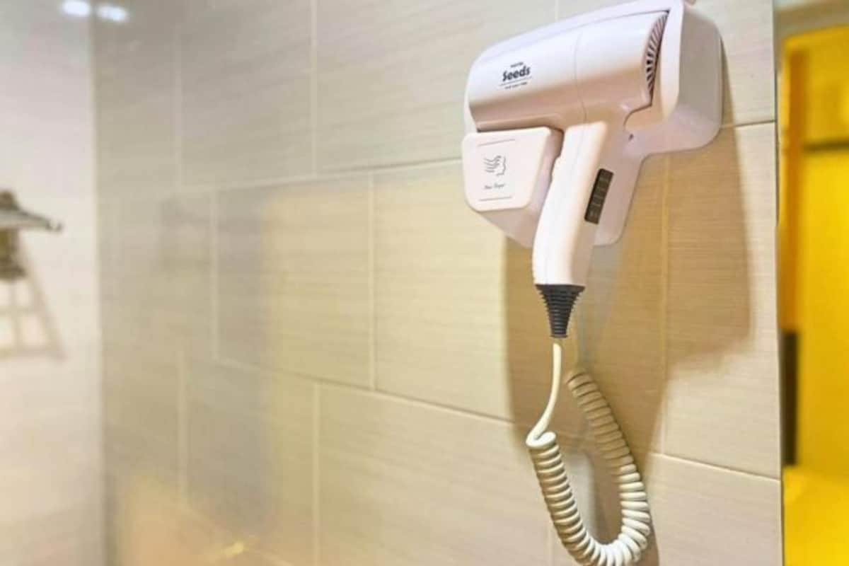 Un secador de pelo fijado a la pared con azulejos y un cable.