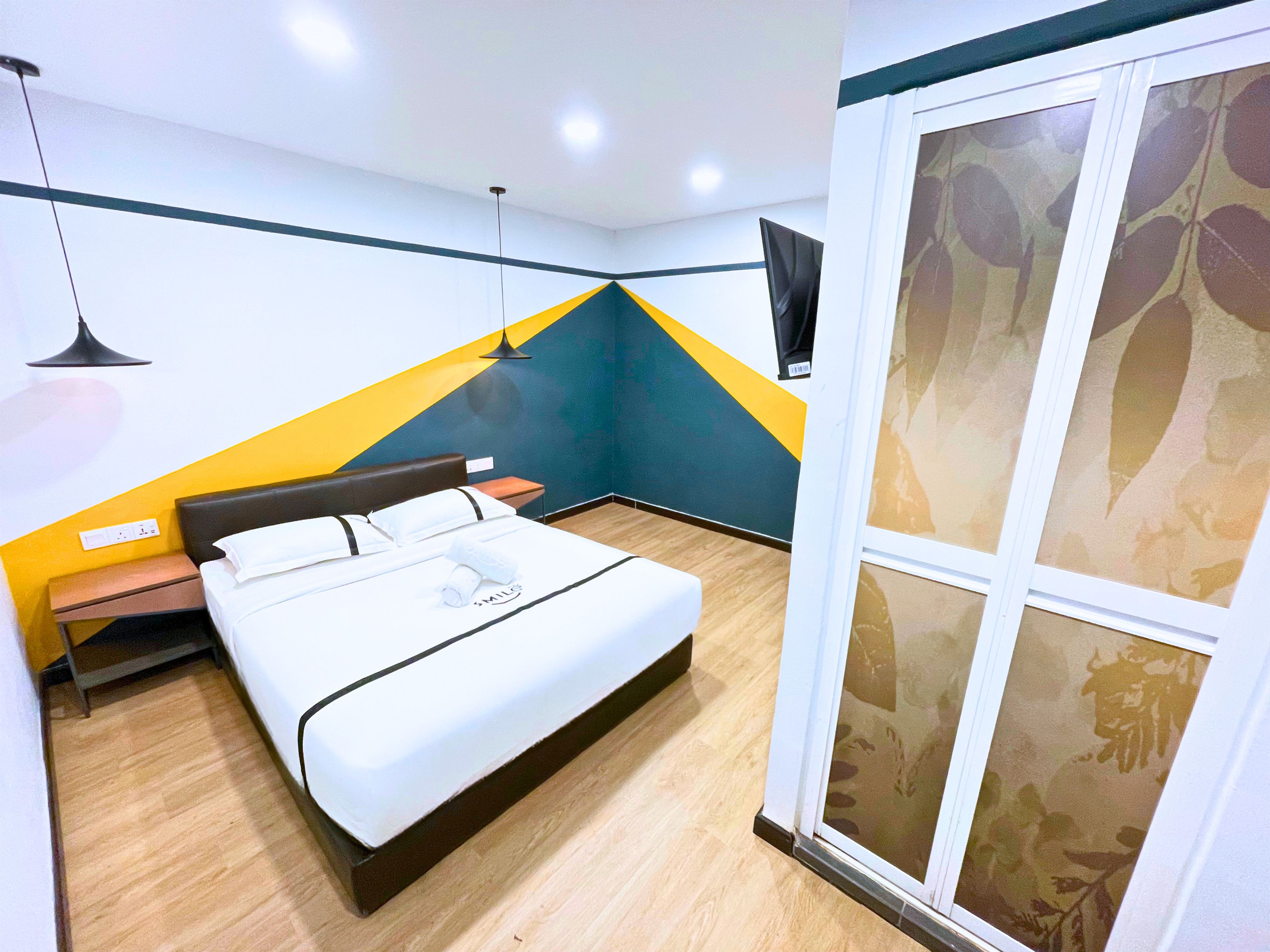 A hotel room with a bed, bedside table, lamp, and a large window with a view.