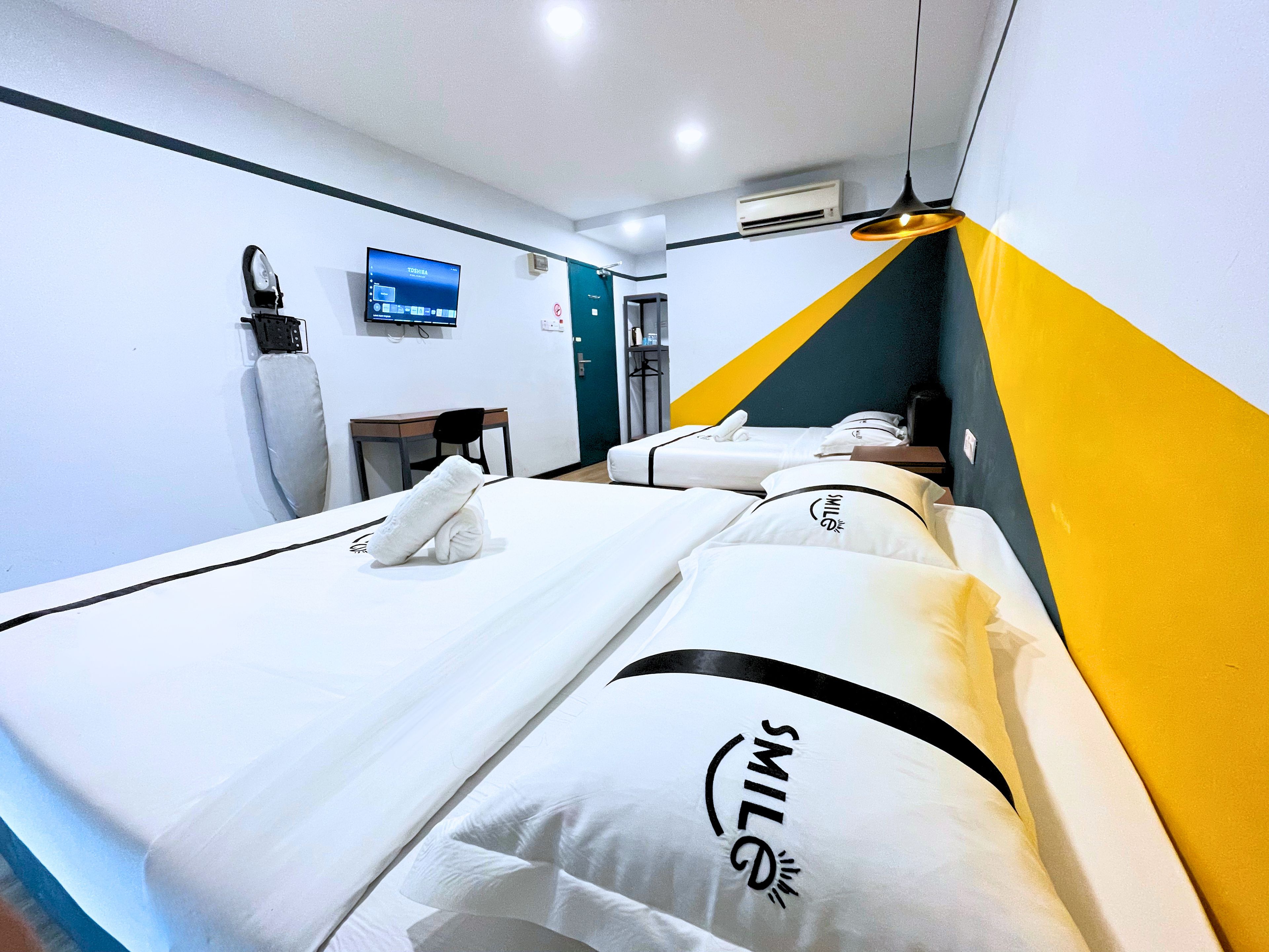 Una habitación de hotel con una cama, un escritorio, una silla, un televisor y un equipo de aire acondicionado.