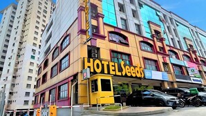 Um hotel de vários andares com uma placa amarela de destaque que diz 'HOTEL SEEDS'.