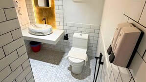 Um banheiro compacto com pia branca, vaso sanitário, espelho e dispensador de sabonete.