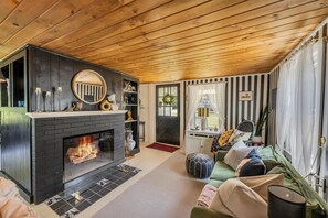 Cozy living room with a central fireplace, comfortable seating area, and decorative accents.