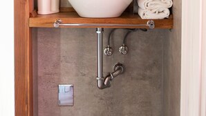 Un baño con lavamanos blanco, espejo y barra para toallas.
