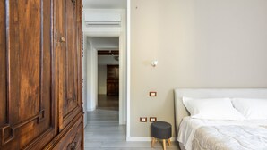 A bedroom with a wooden wardrobe, a bed with white linens, and a small stool. - Varenna Vintage by Wonderful Italy (Perledo)