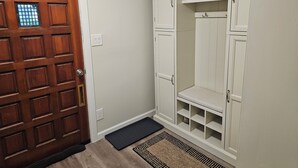 A hallway with a wooden door, a white closet with shelves, and a black mat at the entrance. - Quiet 2bd 1ba ranch with off street parkingWalking distance to downtown/beach. (Lake Geneva)