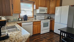 A kitchen with wooden cabinets, a white microwave, a stove, and a refrigerator. - Quiet 2bd 1ba ranch with off street parkingWalking distance to downtown/beach. (Lake Geneva)