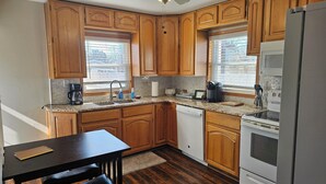 A kitchen with wooden cabinets, a built-in oven, a refrigerator, and a dining table with chairs. - Quiet 2bd 1ba ranch with off street parkingWalking distance to downtown/beach. (Lake Geneva)