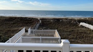 Une vue sur la plage avec une terrasse en bois blanc et une balustrade blanche.
