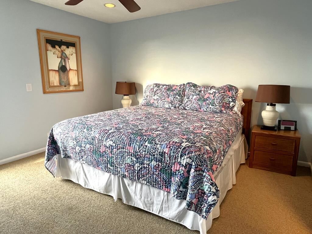 Ein Schlafzimmer mit einem großen Bett, zwei Nachttischen inklusive Lampen und einem gerahmten Bild an der Wand.