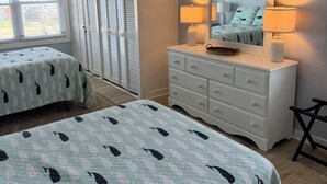 Ein Schlafzimmer mit zwei Betten, einem Schminktisch, einem Spiegel und einem Deckenventilator.