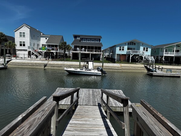 A waterfront property with a dock, a boat, and residential buildings.