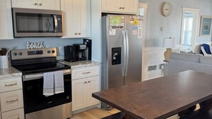 Une cuisine moderne avec des meubles blancs, des appareils en acier inoxydable et une table à manger en bois.