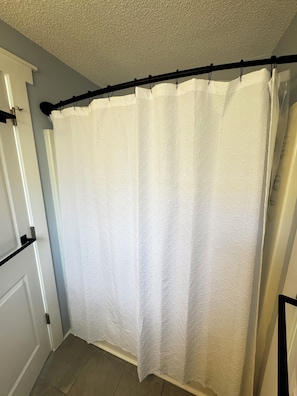 A bathroom with a white shower curtain, a white door, and a light blue wall.