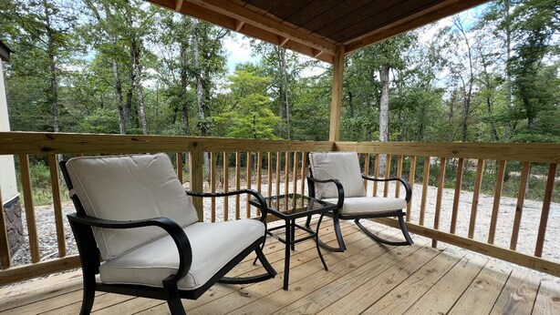 A wooden deck with two rocking chairs and a small table, surrounded by a wooden railing. - Lake Ouachita Hideaway! (Mount Ida)