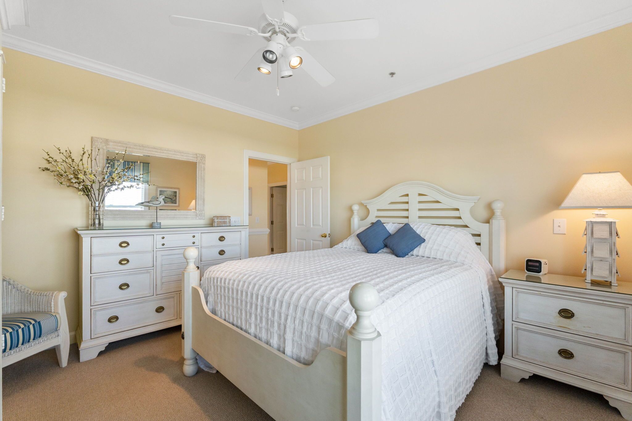 A bedroom with a bed, nightstands, a dresser, a chair, and a ceiling fan.
