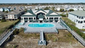 Un grand bâtiment doté d’une piscine, entouré d’une terrasse et relié à un pont.