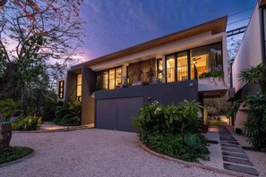Una casa moderna con un garaje grande, un porche cubierto y un camino de entrada de grava.