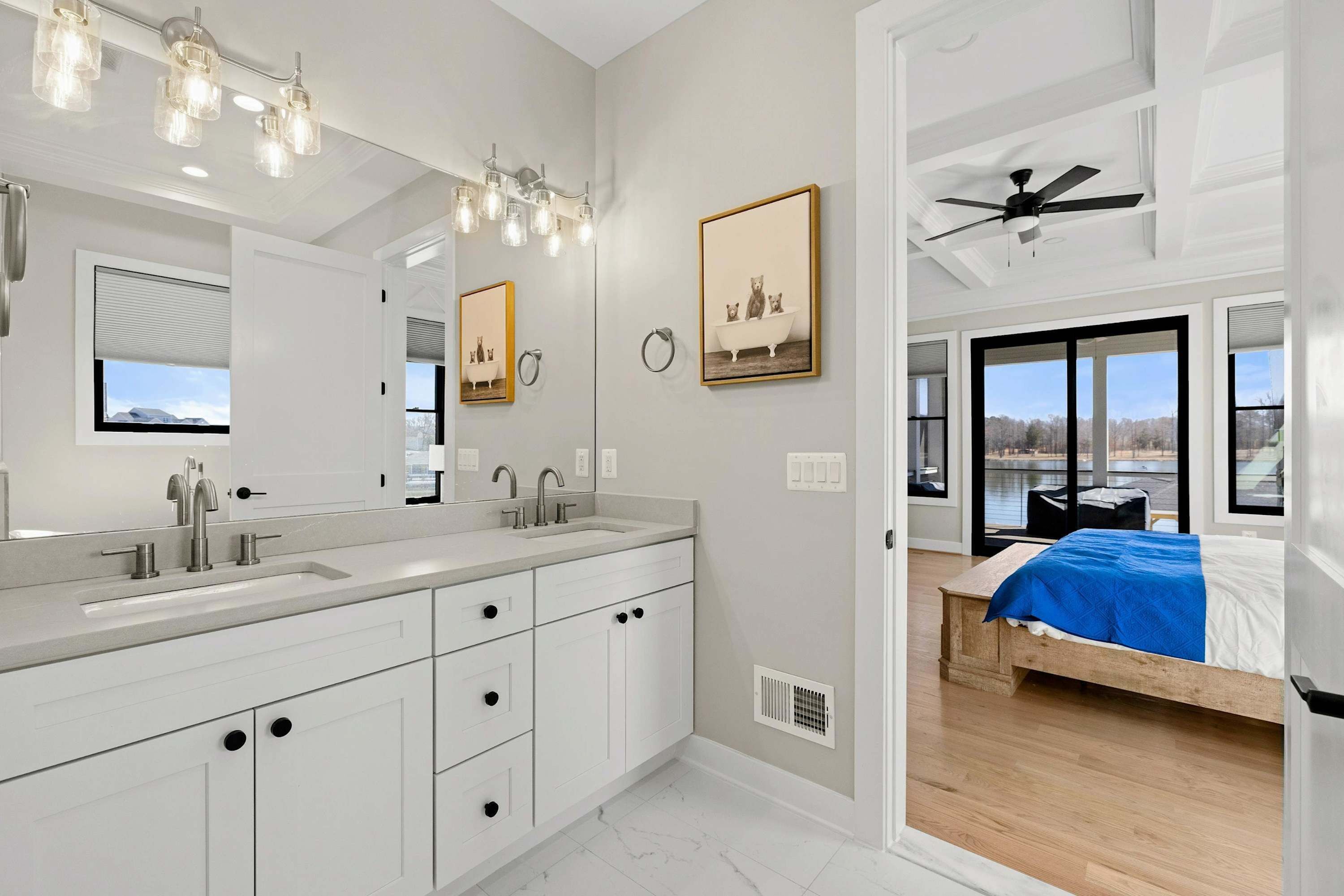 A modern bathroom with a large vanity, dual sinks, and a ceiling fan.