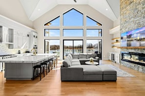 A spacious kitchen with a large island, a cozy living area with a sectional sofa, and a stone accent wall. - Serene Lakefront Lake Anna, Beach, Dock, Pool (Louisa County)